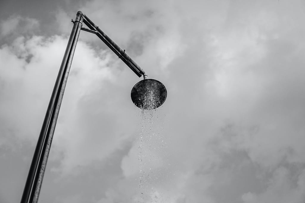 Close-up of a shower head with water flowing out in a steady stream. The water droplets create a refreshing and invigorating effect.