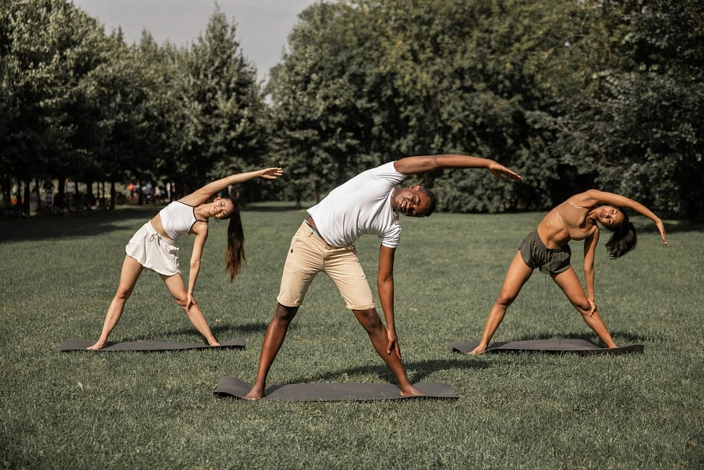 Three individuals practicing a yoga side bend pose, demonstrating flexibility and strength benefits of yoga for athletes.