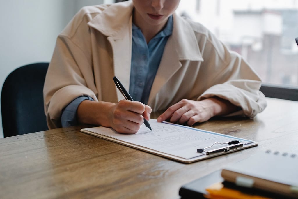 A candid photo of a person engrossed in writing on a clipboard. Capturing the moment of focused productivity and organization.